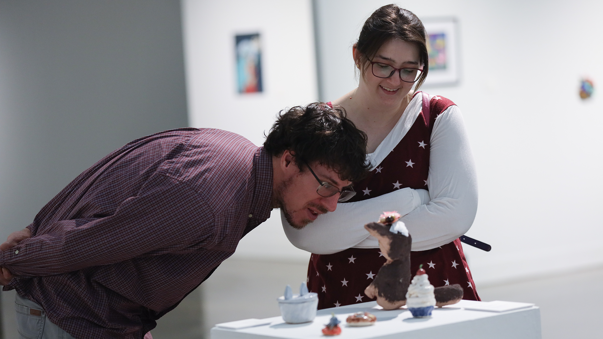 two individuals bend down to take a closer look at a small sculpture